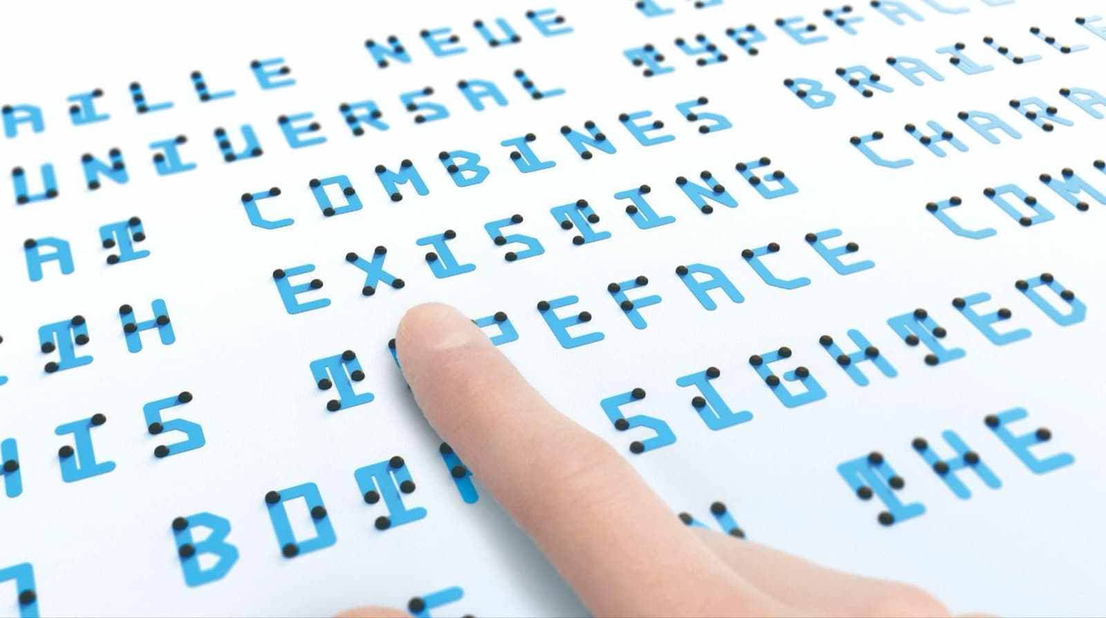 点字と英字が一体になった青いフォント「Braille Neue」で書かれた文章の上を、指先がたどっている。