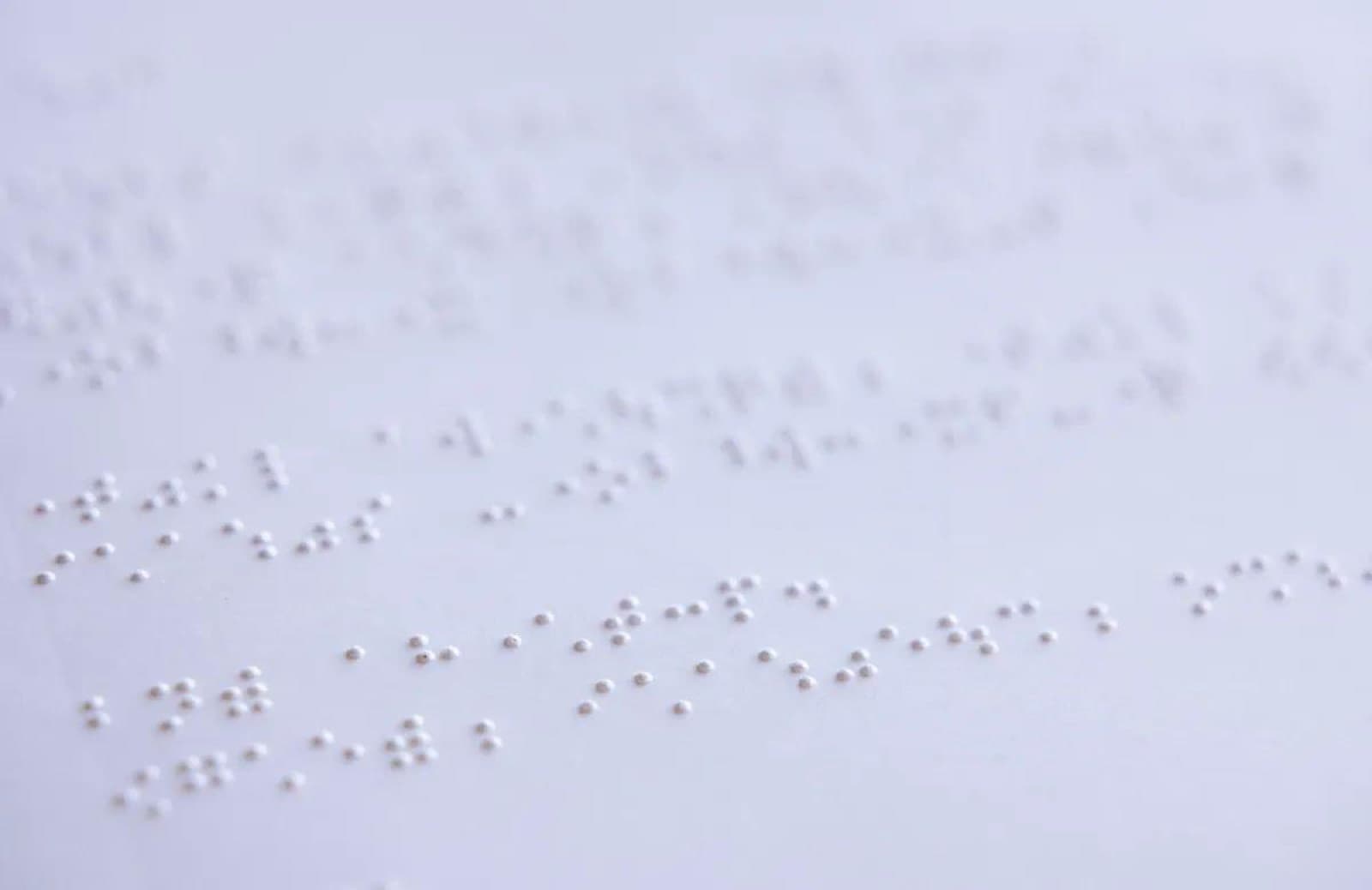 白い紙に点字が打たれ、ぽつぽつと浮き出た点が並んでいるクローズアップ。